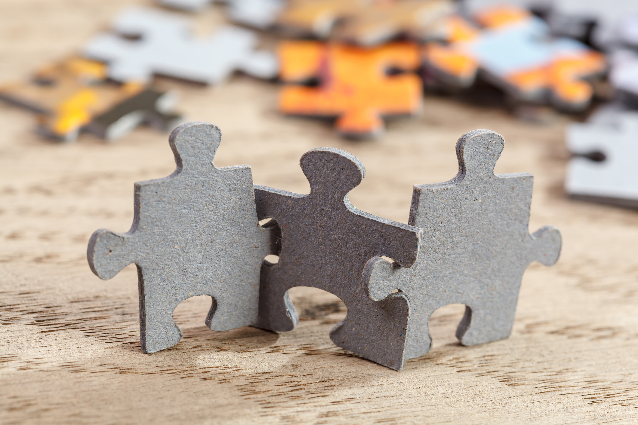 Concept of teamwork: Three jigsaw puzzle pieces on a table joint together. Shallow depth of field