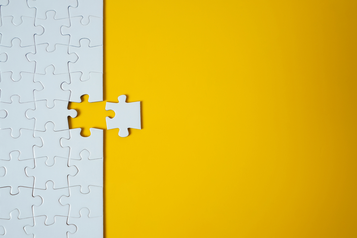 White jigsaw puzzle on yellow background. Team business success partnership or teamwork.