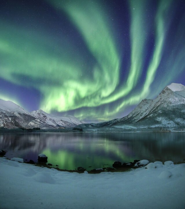 Northern lights above a lake and mountains