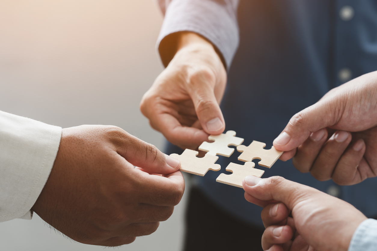 business people team holds in hand a jigsaw or puzzle pieces in the office for concept of troubleshooting, teamwork, Unity and partnership. success and strategy concept.