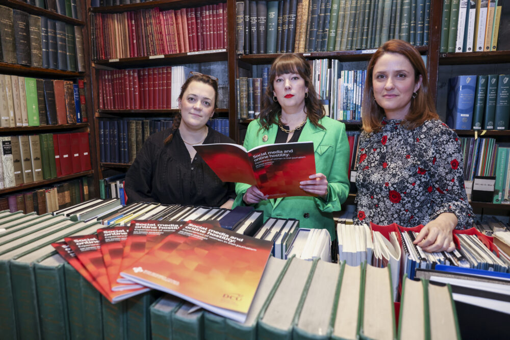 Three researchers pictured holding a report in a library