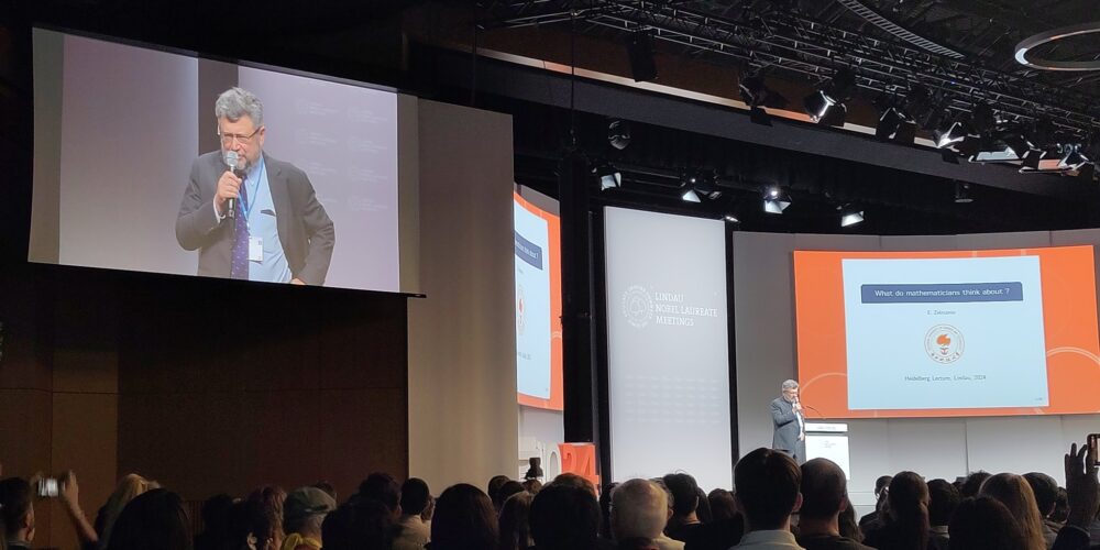 Image of lecture hall with man speaking holding microphone