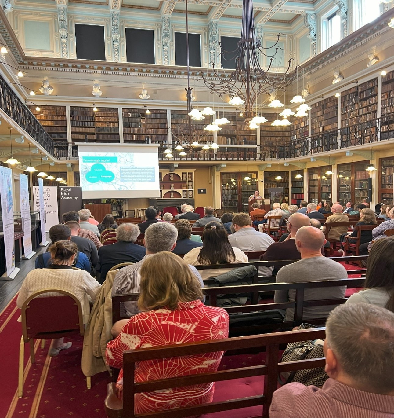 Large crowd in old library sitting facing a speaker