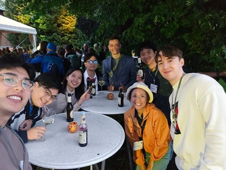 Group photo of young researchers outside sitting around a table, all smiling