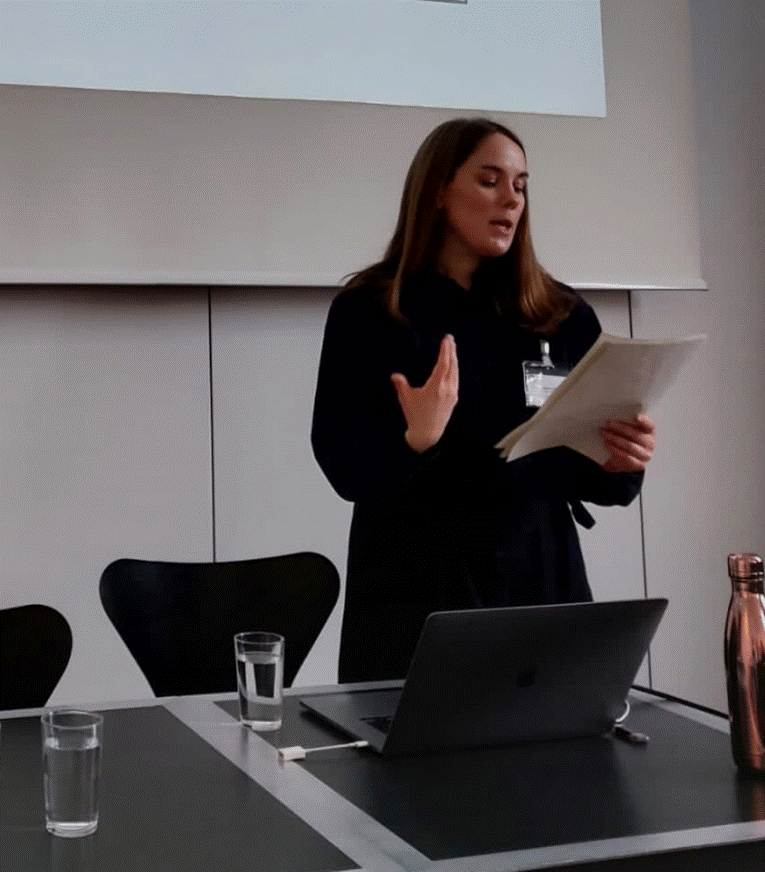Image of researcher Sophie Franklin, holding researcher paper and speaking